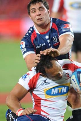 James Kamana of the Lions is tackled by Nick Phipps of the Rebels.