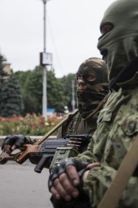 Armed pro-Russian separatists look on at a town centre in Snizhnye.