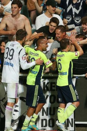 Victory's Archie Thompson, Nathan Coe and Leigh Broxham celebrate with fans after beating the Wanderers 2-0.