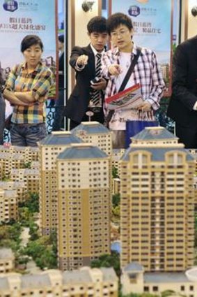 Visitors look at model apartments at a real estate exhibition in Shenyang.