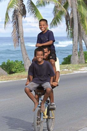 Nauruan boys share a bike ride on the island's main road.
