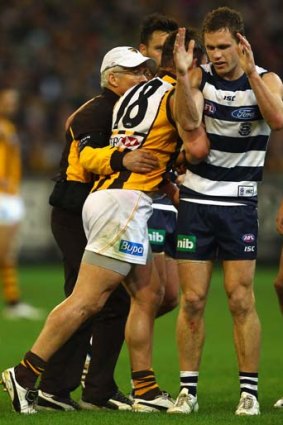 Geelong's Joel Selwood tangles with Hawthorn's Brent Guerra as the Hawthorn player is helped from the field.