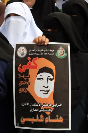 A Palestinian woman holds a banner reading 'Enough to administrative detention' during a rally in Gaza City.