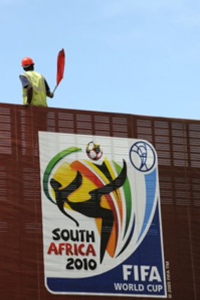 Rainbow nation of football lovers ... a construction worker sits by a giant banner in Cape Town.