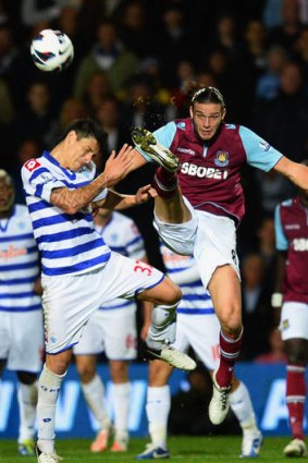 Andy Carroll of West Ham United (right) jumps with Alejandro Faurlin of Queens Park Rangers.