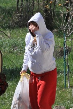 A unidentified person carries a bag from the house where seven infant bodies were discovered.