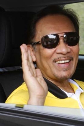 Opposition leader Anwar Ibrahim waves to photographers as he leaves his residence in Kuala Lumpur .