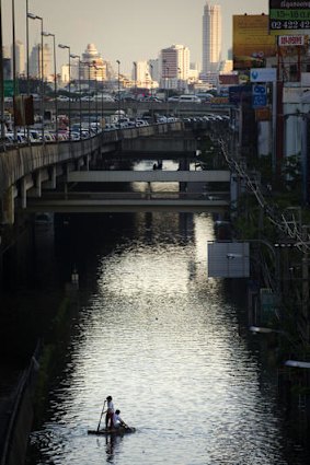 Local residents paddle a raft over a flooded lower street in an area near the Chao Praya river in Bangkok.