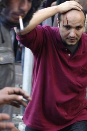 A protester's head bleeds from a stone thrown as protesters battle with military police during clashes.
