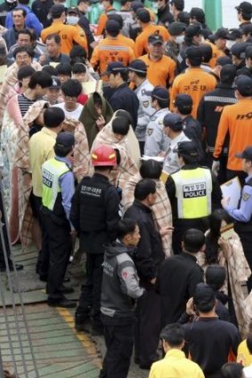 Passengers are escorted by rescue personnel at the port of Jindo, south of Seoul.