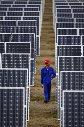 A worker inspects solar panels at a solar farm in Dunhuang, China.