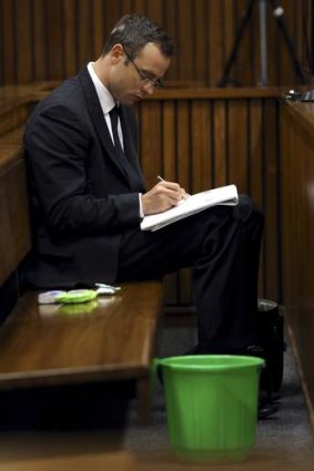 Olympic track star Oscar Pistorius takes notes with a bucket next to him during court proceedings in Pretoria.