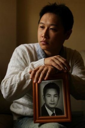 Tommy Du at his home in Sydney, holds a photograph of his father Du Zuying