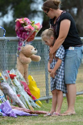 Friends arrive at the Tyabb oval to place flowers near the scene.