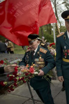 World War II veterans carry flowers given to them by people attending Victory Day celebrations on Friday.
