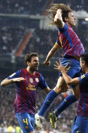 Raising the Barca &#8230; Carles Puyol celebrates his equaliser against bitter rivals Real Madrid.