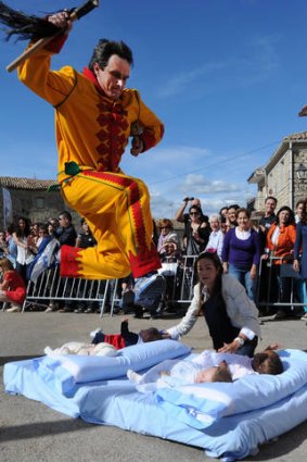 Leap of faith: A man playing the devil jumps over babies in the village of Castrillo de Murcia in Spain, the latest eurozone country to go cap in hand.