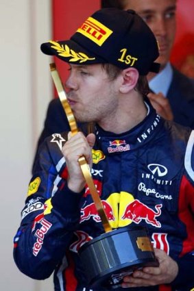 Vettel kisses his trophy on the podium.