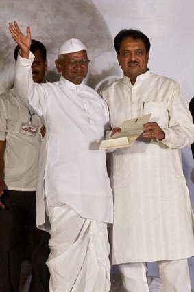 Anna Hazare waves as he accepts a letter on the agreement.