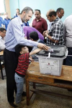 A man casts his vote with the help of his son at a polling station in Al-Sharqya.
