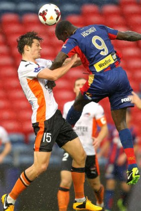 Up for it: Emile Heskey of the Jets challenges the Roar's James Donachie for the ball.