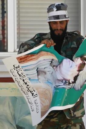 A rebel rips up a poster of Libyan leader Muammar Gaddafi after taking control of Zawiyah.