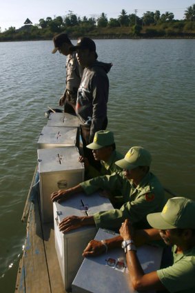 Election officers take ballot boxes by boat to the village of Barombong in South Sulawesi province.