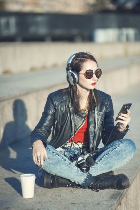 A hipster girl in leather jacket and glasses listening to music; could she be a Millennialoomer? 