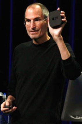 Apple chief executive Steve Jobs holds the new, smaller Apple TV device.