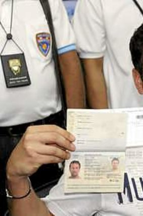 Italian Luigi Maraldi, whose stolen passport was used by a passenger boarding a missing Malaysian airliner, shows his passport as he reports himself to Thai police at Phuket police station.