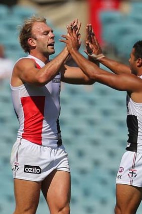 An exhausted Beau Wilkes of the Saints (left) celebrates with a teammate after kicking a goal against Adelaide.