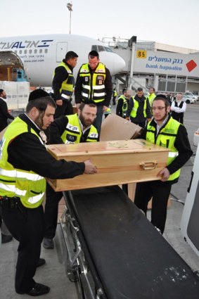 Volunteers  unload a coffin carrying a victim of the Toulouse shooting in France for burial in Israel.