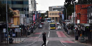 A lone person walks across Moore Street,Liverpool as Sydney bunkers down under tightened restrictions. 