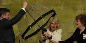Queen Camilla hands her umbrella to an aide as she arrives to attend a musical evening at Salisbury Cathedral.