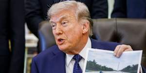 US President Donald Trump holds up a photo of the Lincoln Memorial reflecting pool during a news conference.