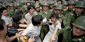 A woman is caught between civilians and Chinese soldiers,who were trying to remove her from an assembly near the Great Hall of the People in Beijing,on June 3,1989. 