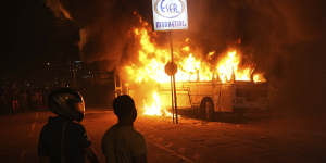 Protesters watch as a bus is set on fire outside the presidence’s residence on April 1.