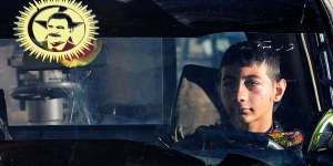 A young YPG fighter sits in a car in the village of Tel Marouf,the face of PKK founder Abdullah Ocalan on the windscreen. 