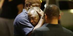 Worshippers embrace following a group prayer across the street from the scene of a shooting Wednesday.