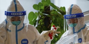 Health workers wearing protective suits store COVID-19 test samples at a hotel used for COVID quarantine on March 20 in the Yanqing district of Beijing. 