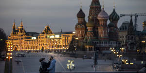 A couple enjoy warm weather on a bridge with St. Basil’s Cathedral,right,and an almost empty Red Square after sunset in Moscow,Russia.