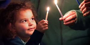 Four-year-old Riley Gillet,of Orlando,lights a candle with her family,marking the beginning of the traditional Jewish holiday of Hanukkah,during the Chabad of Greater Orlando's"Chanukah on the Park"celebration in Winter Park,Fla.,late Sunday,Nov. 28,2021. Held at Central Park,the event included the lighting of a giant menorah,live performers,music and dancing. Jews worldwide will celebrate Hanukkah through Dec. 6. (Joe Burbank/Orlando Sentinel via AP)