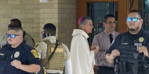 San Antonio Archbishop Gustavo Garcia-Siller waits as police create a barrier as guests arrive for the joint funeral service for Joe and Irma Garcia.