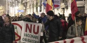 People hold a large banner that reads “No to Vaccination - Our Children are not your guinea pigs” during a protest against vaccinations,the introduction of the green pass and COVID-19 related restrictions in Bucharest.