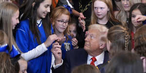 US President Donald Trump hands out pens after signing an executive order barring transgender female athletes from competing in women’s or girls’ sports.