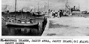 This undated photo discovered in the U.S. National Archives by Les Kinney shows people on a dock in Jaluit Atoll,Marshall Islands. A new documentary film proposes that this image shows aviator Amelia Earhart,seated third from right,gazing at what may be her crippled aircraft loaded on a barge. 