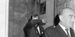 Mr Geoffrey Chandler covers his face as he arrives at Central Court,Sydney,on 23 May 1963. 