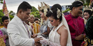 A bride and groom exchange wedding rings in Yogyakarta.