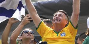 Bolsonaro holds an Israeli flag on Sunday. He and some of his former aides are under investigation into allegations they plotted a coup to remove his successor,Lula,who is at odds with Israel over Gaza.