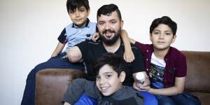 Eight-year-old twins Ahmed and Mohammed al-Shnen and 10-year-old Ali (right) with their father at his home. 